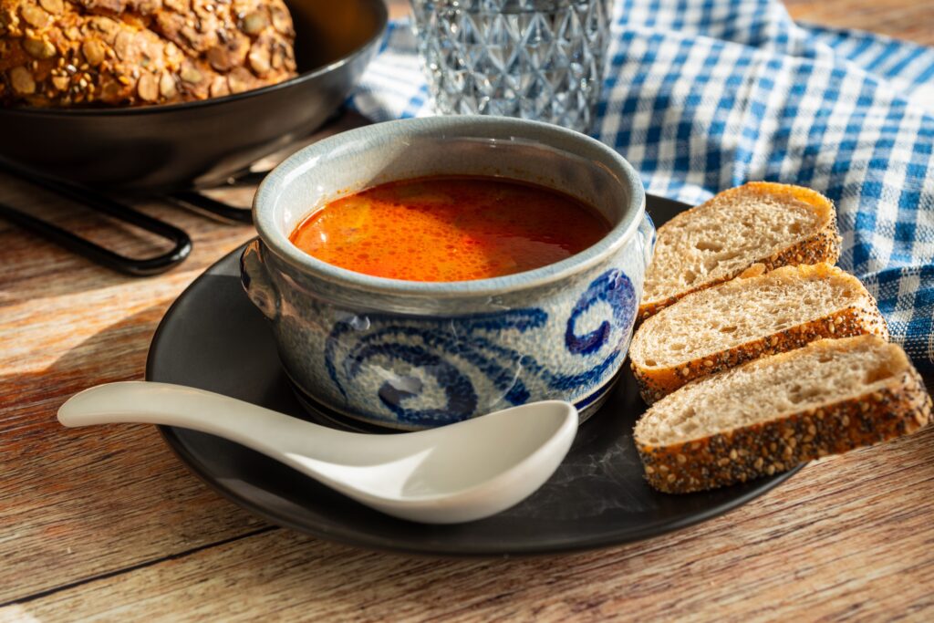 Hearty solyanka soup served with slices of rustic bread on a table.
