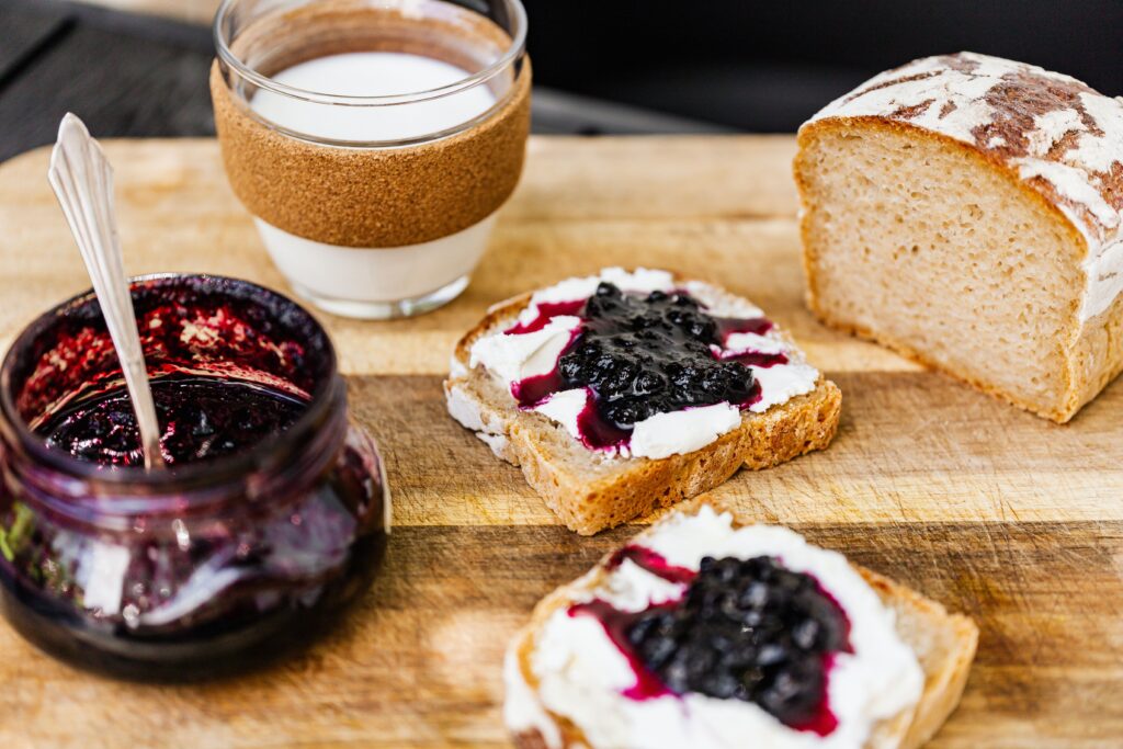 A rustic breakfast setup with homemade bread, jam, and fresh milk.