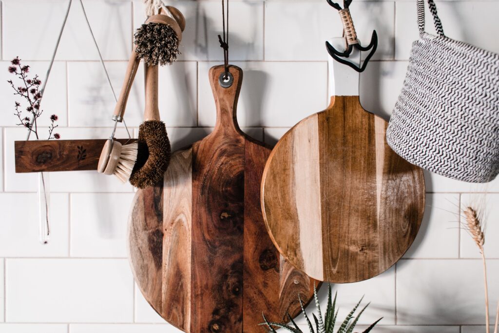 Charming wooden kitchenwares hang stylishly on a white tiled wall, perfect for rustic decor.