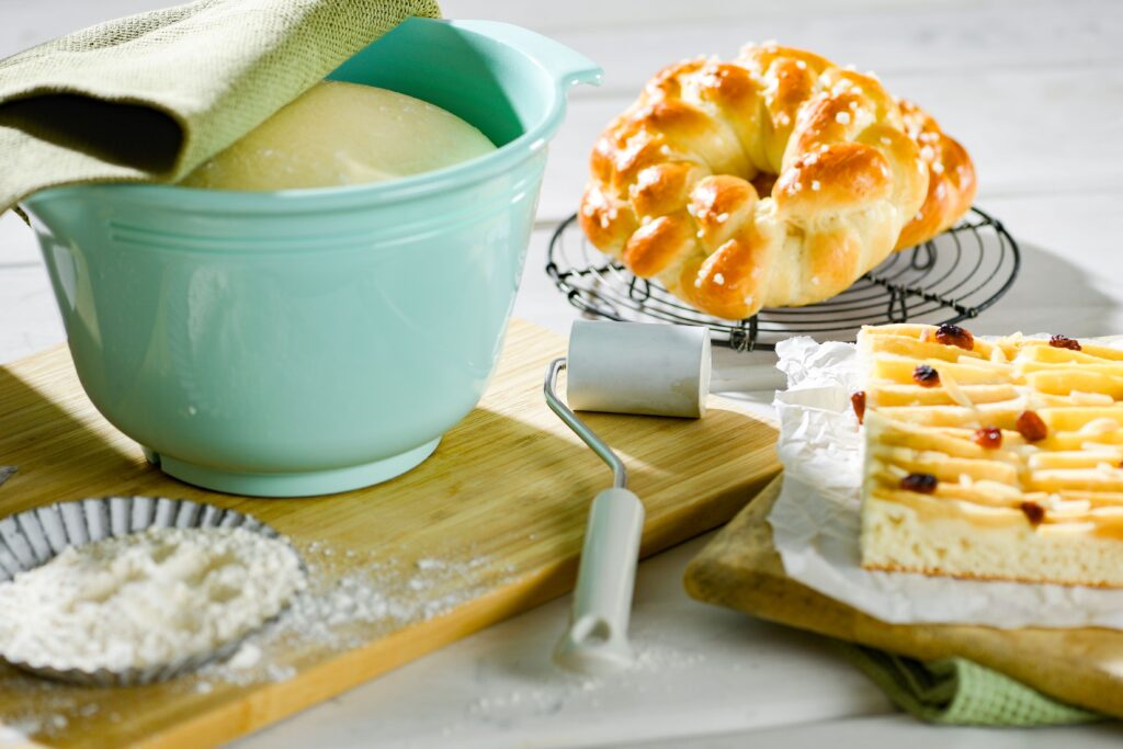 Freshly baked bread and dough in a bowl with baking ingredients on a cutting board.
